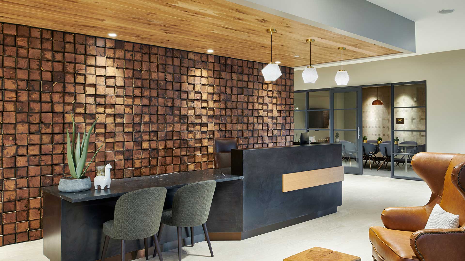 Modern Epoque Golden leasing lobby with wood accent wall, reception desk, pendant lighting and leather lounge chair.