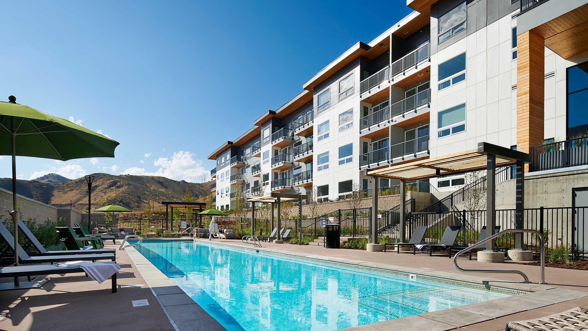 Epoque Golden outdoor swimming pool with lounge chairs, apartment balconies and foothill views.