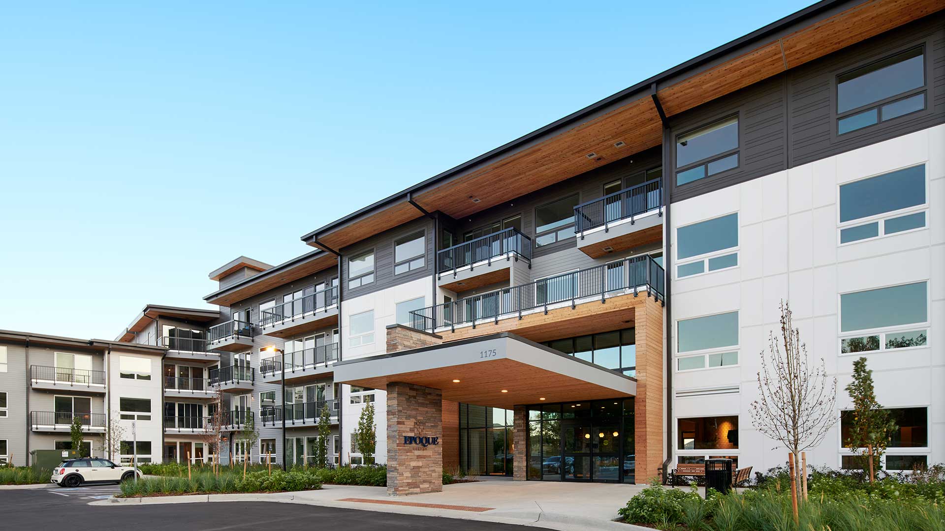 Exterior of Epoque Golden apartments with covered entrance, balconies, modern siding and landscaped grounds.