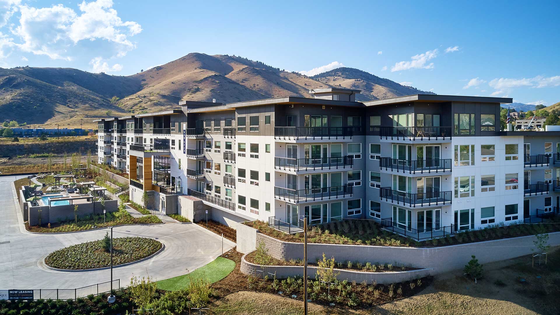 Aerial view of Epoque Golden apartments with balconies, outdoor pool, landscaped grounds and surrounding foothills.