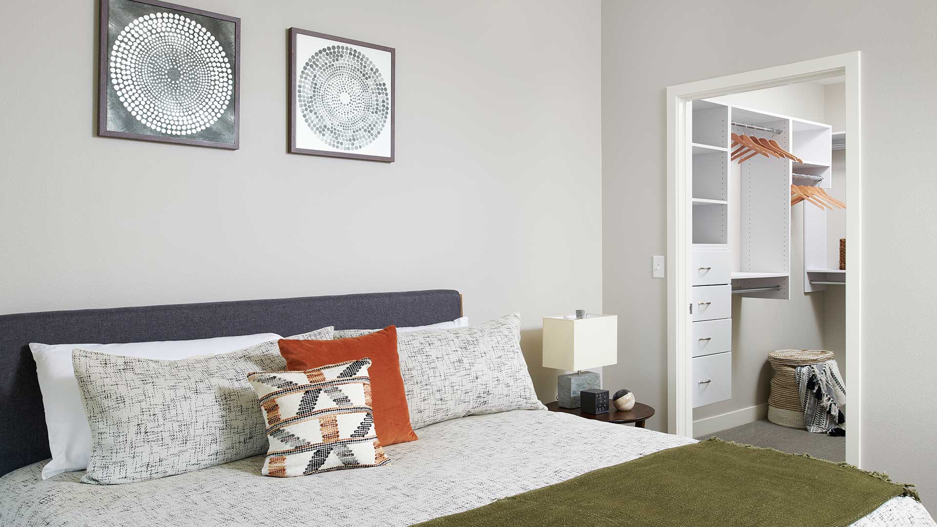 Epoque Golden apartment bedroom with large bed, modern decor and direct access to a walk-in closet with built-in shelving and drawers.