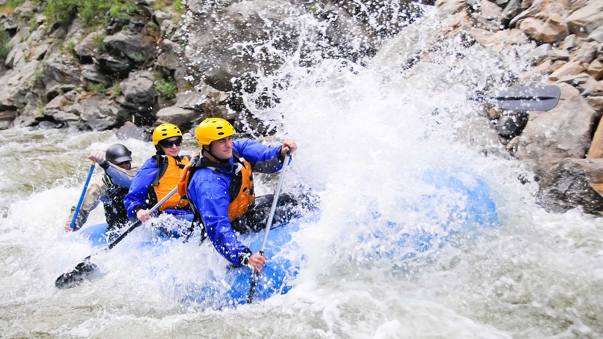 Group of rafters navigating whitewater rapids through a rocky Colorado canyon.