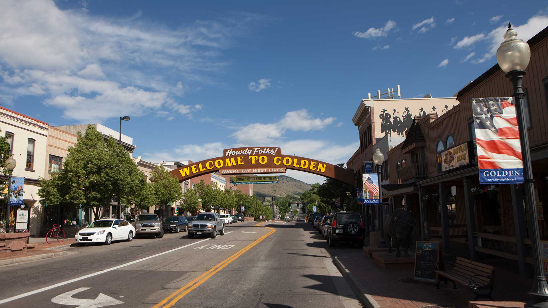 Downtown Golden, Colorado, with the Welcome to Golden arch spanning Washington Avenue, historic storefronts and foothills in the distance.